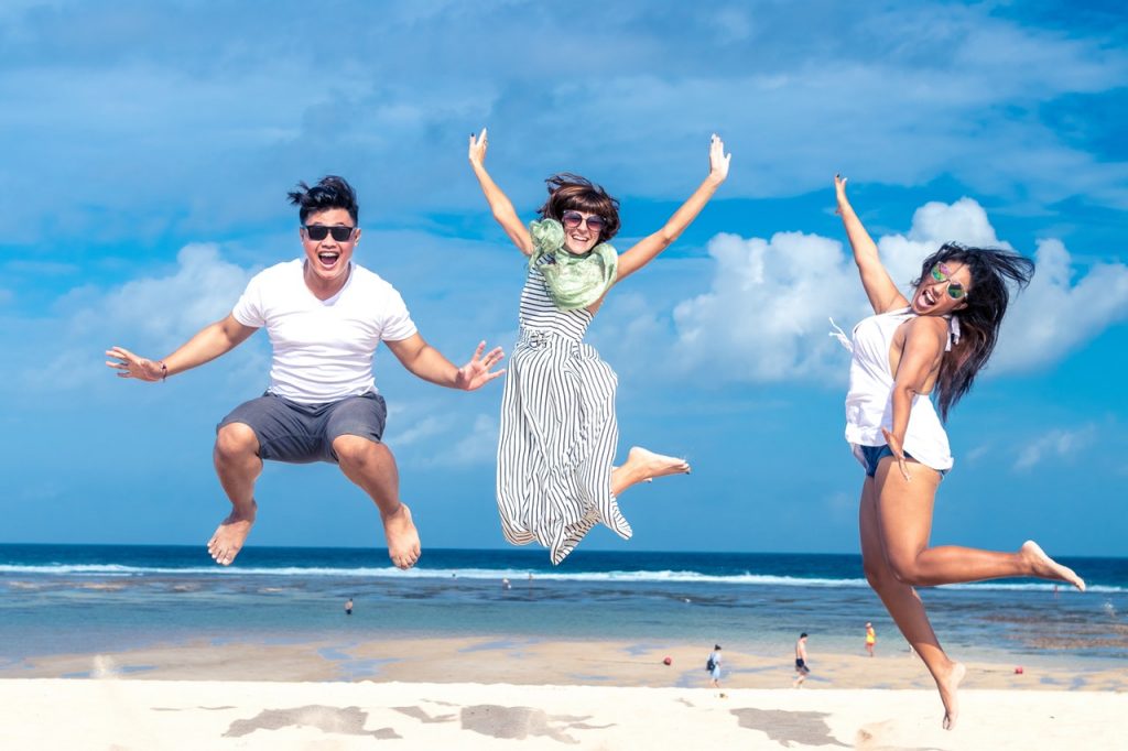a group of people jumping in the air on a beach